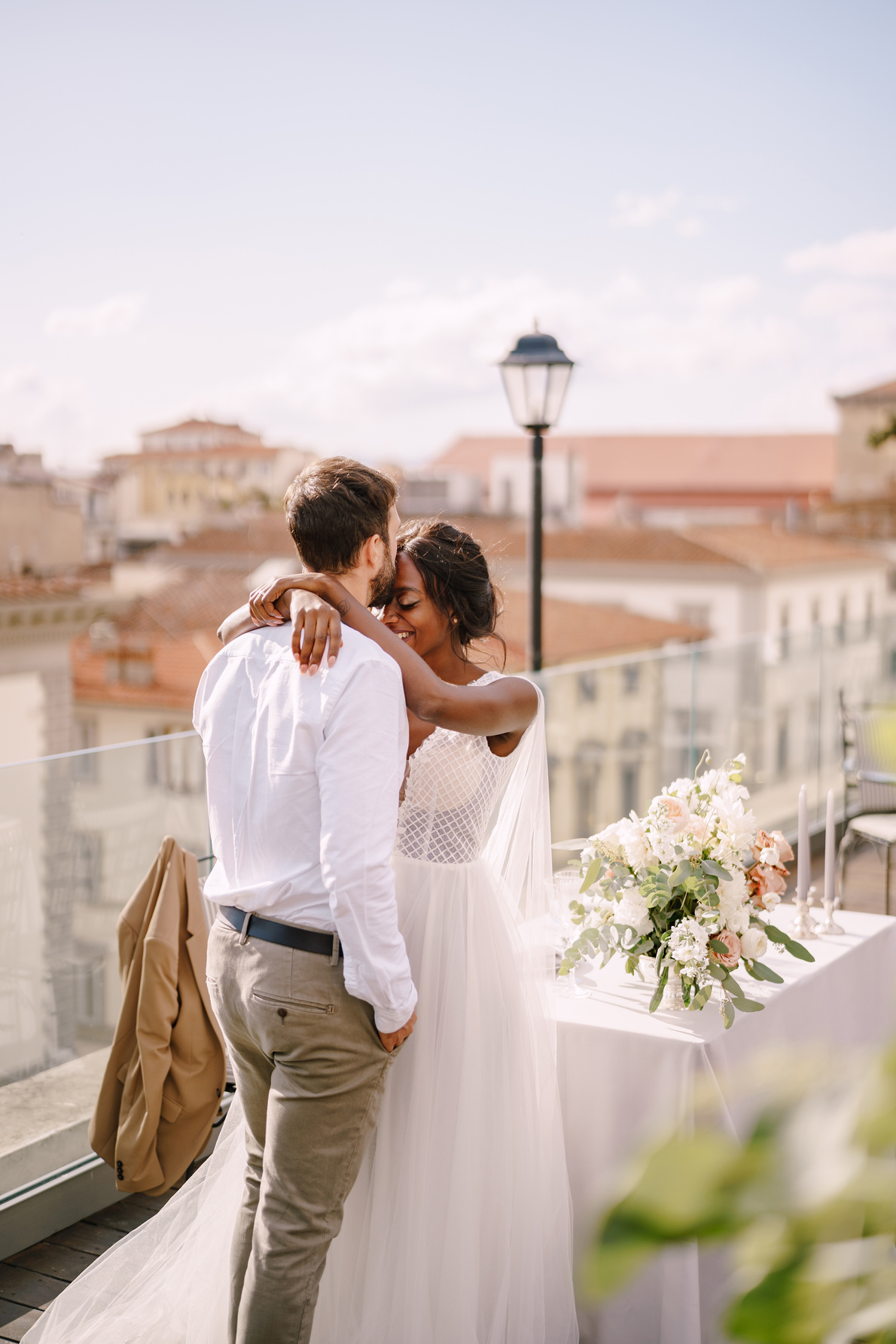 Destination fine-art wedding in Florence, Italy. Interracial wedding couple. African-American bride and Caucasian groom stand near the table for a wedding dinner.